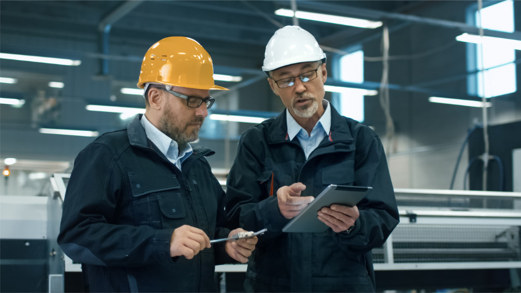 two-engineers-in-hardhats-discuss-information-on-a-tablet-computer-picture-id838527388