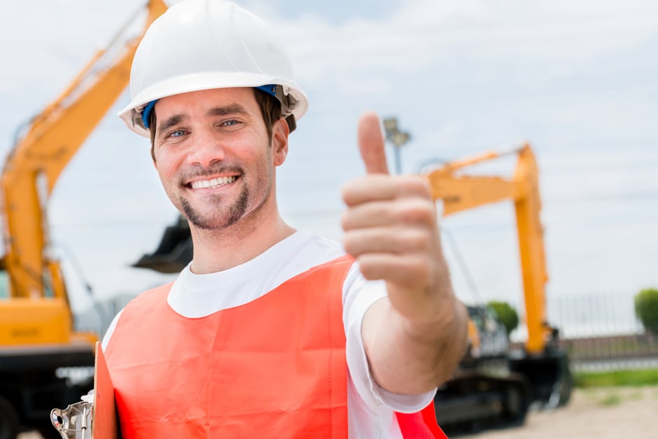 Happy contractor at a building site with thumbs up